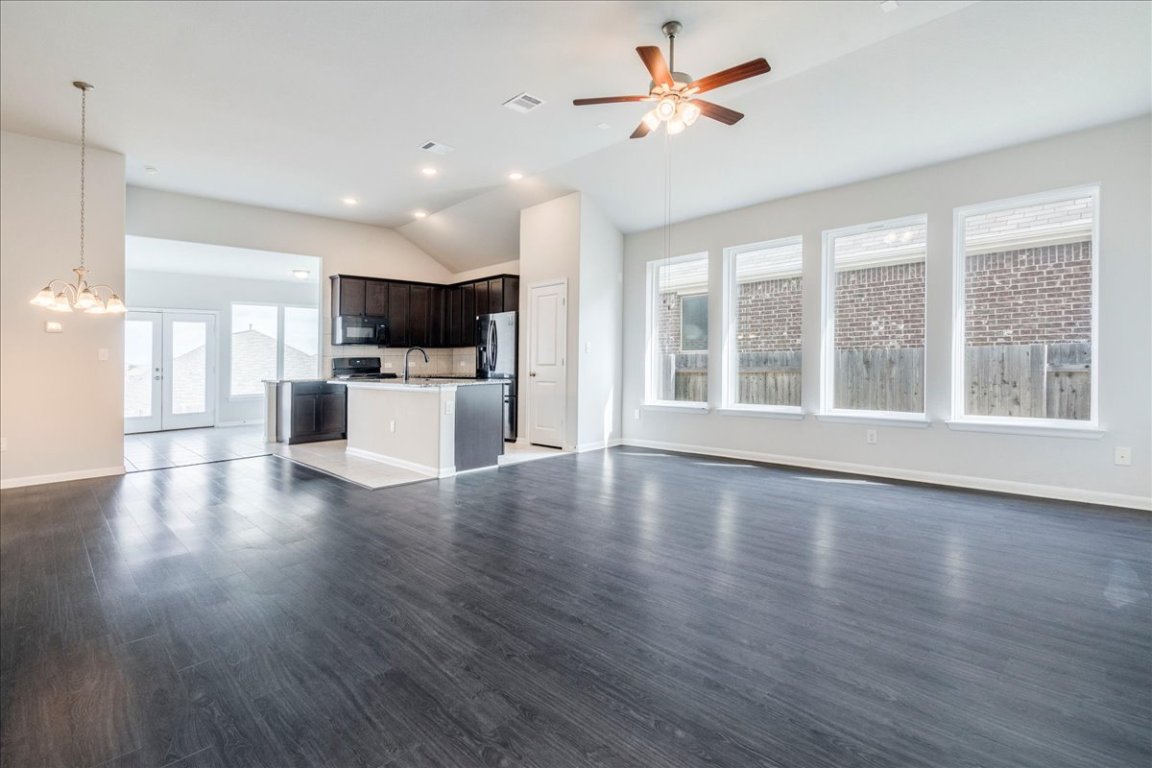 a view of an empty room with a kitchen and wooden floor