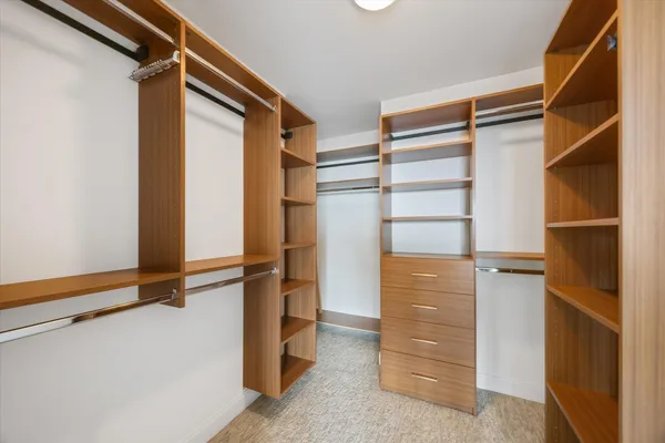 a view of walk in closet with clothes and shoes