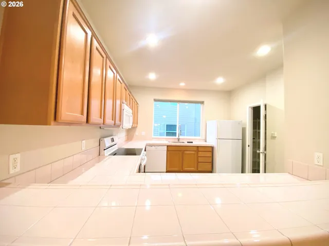 a large kitchen with stainless steel appliances kitchen island granite countertop a refrigerator and a sink