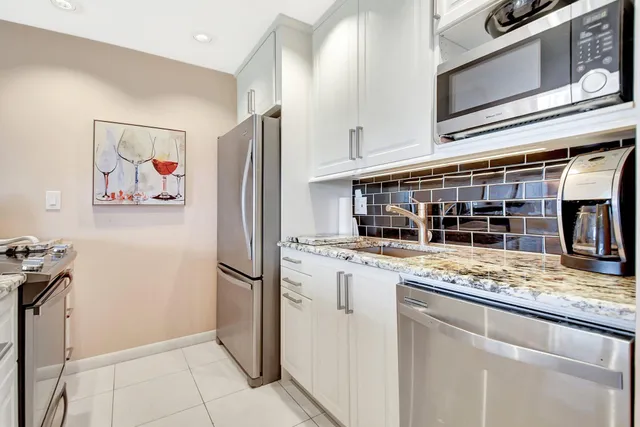 a kitchen with stainless steel appliances granite countertop a refrigerator and a stove top oven
