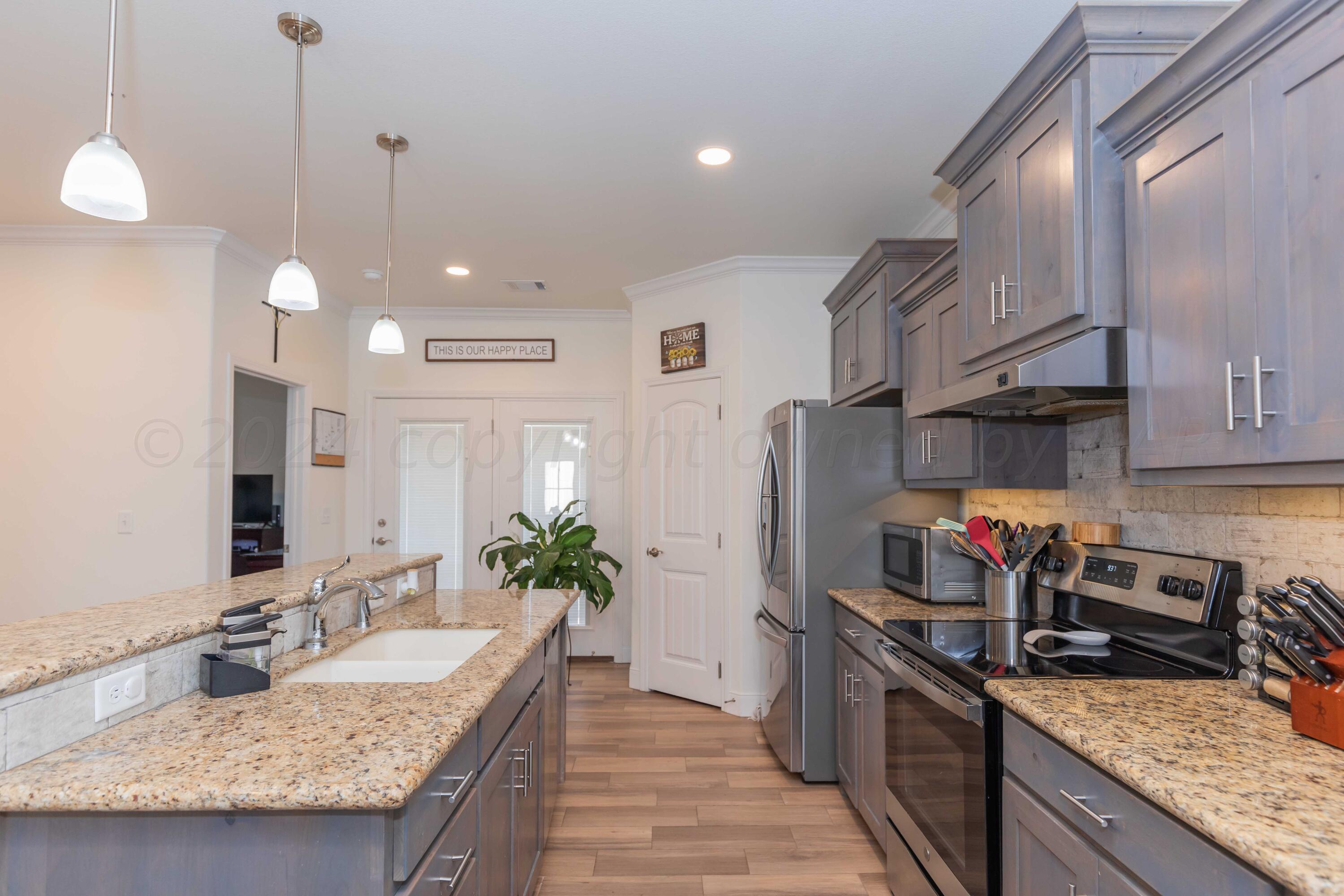 a kitchen with granite countertop kitchen island stainless steel appliances a sink stove top oven and cabinets