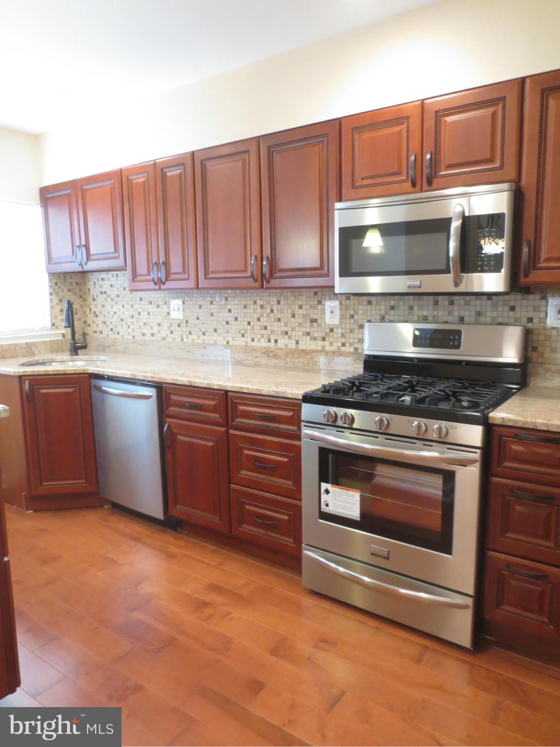 1405 Kitmore Road Baltimore, MD 21239 - Photo 3 of 25 a kitchen with granite countertop a stove top oven microwave and cabinets