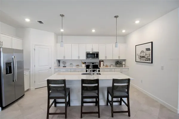 a kitchen with refrigerator and white cabinets