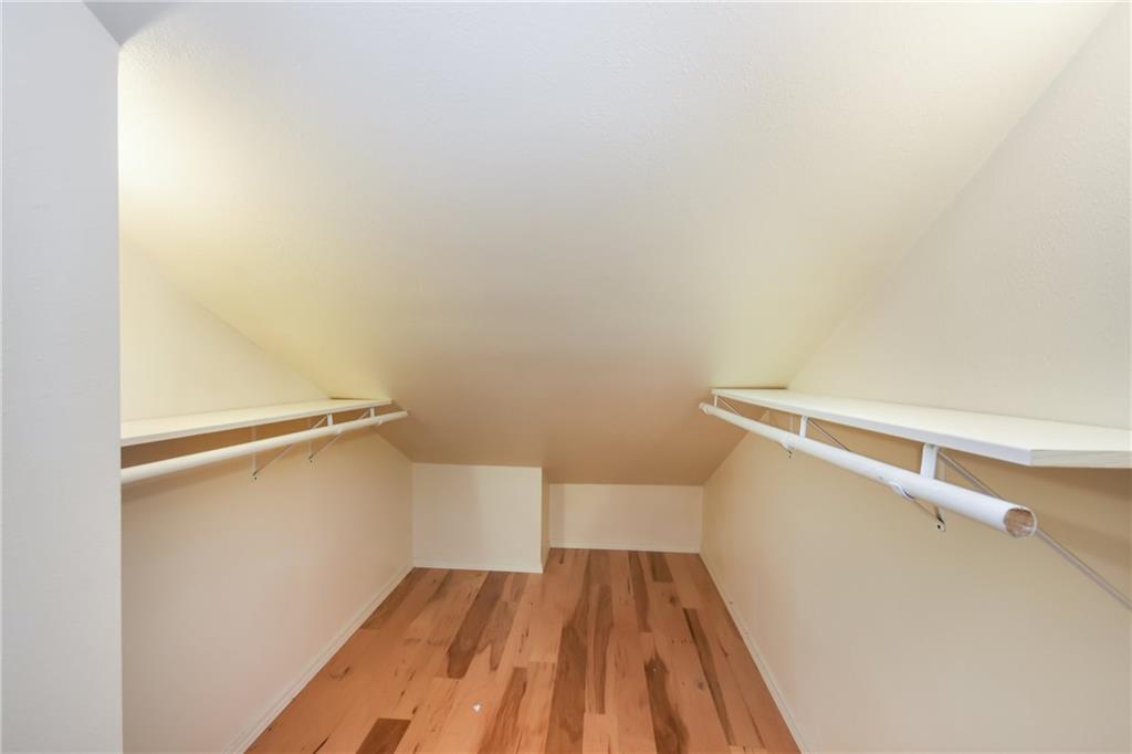 3115 Tom Green Street, Unit 404 Austin, TX 78705 - Photo 16 of 19 Attic storage space featuring wood-finish flooring, sloped ceilings, and built-in shelving with hanging rods