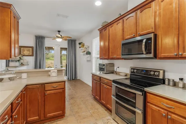 a large kitchen with stainless steel appliances granite countertop a stove a sink and a microwave