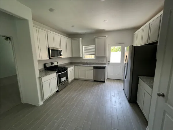a kitchen with a sink a microwave a refrigerator and cabinets