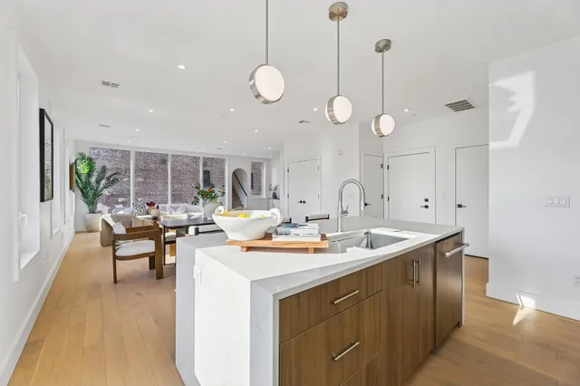 a living room with stainless steel appliances granite countertop a sink a kitchen island a stove and a wooden floors
