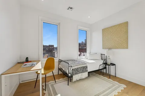 a bedroom with a bed table chair and a wall painting