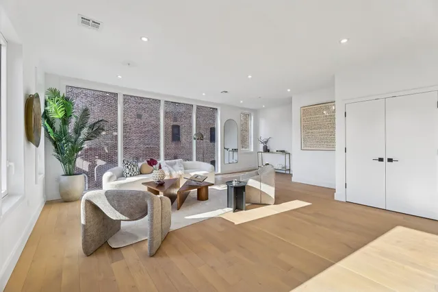 a living room with furniture large window and potted plants