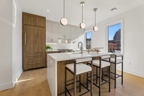 a kitchen with kitchen island a dining table chairs sink and wooden floor
