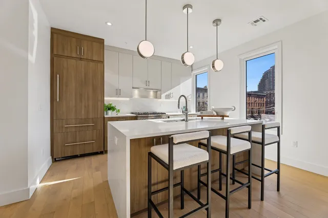 a kitchen with kitchen island a dining table chairs sink and wooden floor