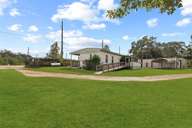 an aerial view of a house with a yard lake and trees all around