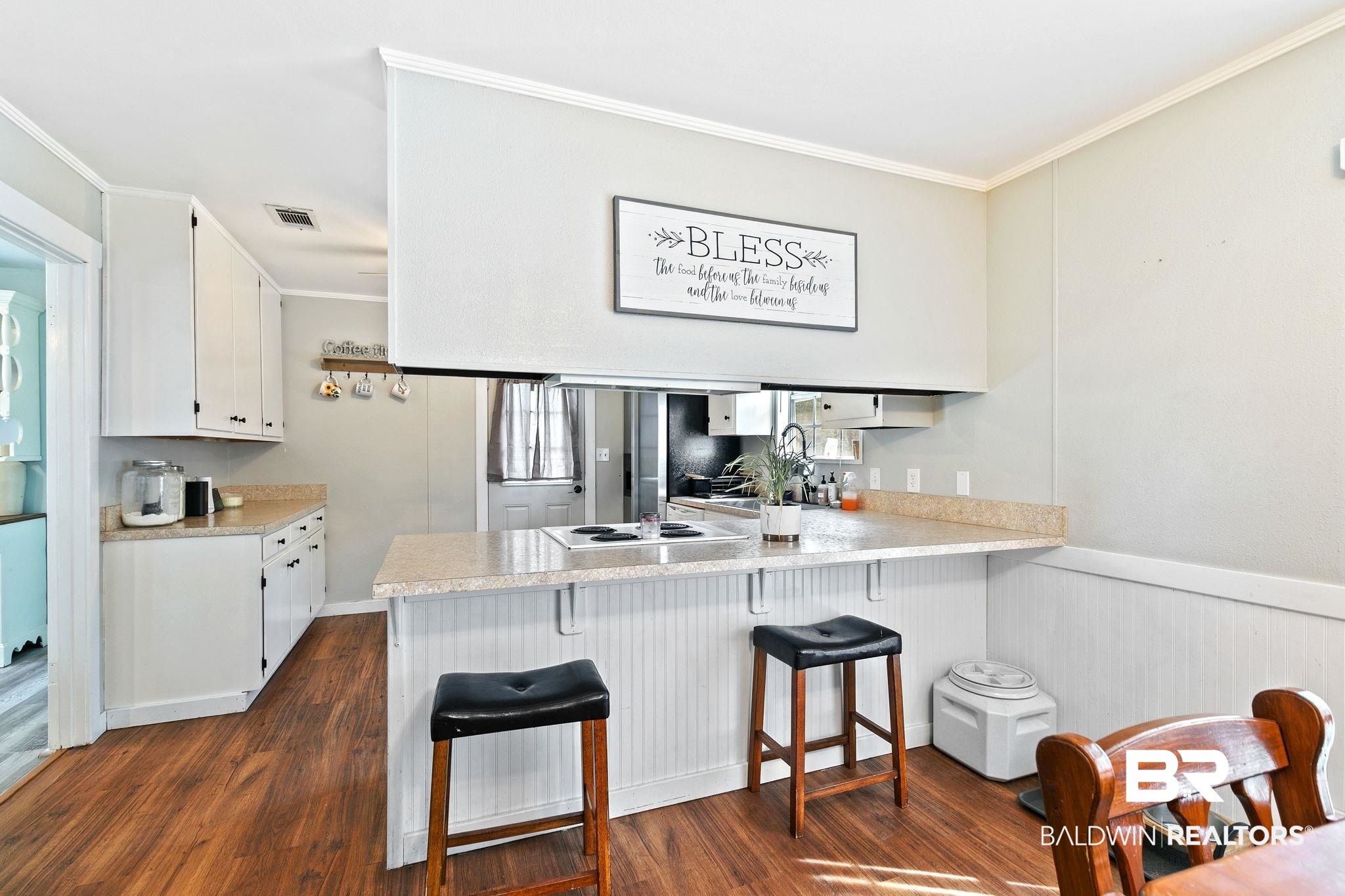14 Lee Circle Daphne, AL 36527 - Photo 27 of 83 Kitchen with crown molding, dark hardwood / wood-style flooring, white cabinets, a breakfast bar area, and kitchen peninsula