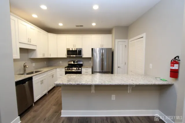 a kitchen with stainless steel appliances granite countertop a sink a stove and a refrigerator
