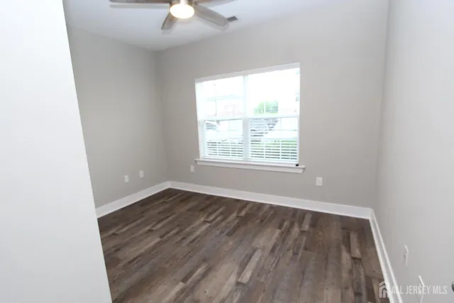 an empty room with wooden floor ceiling fan and window
