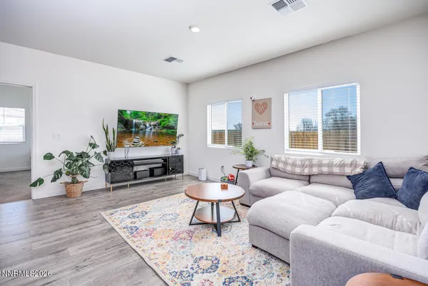 a living room with furniture wooden floor and kitchen view