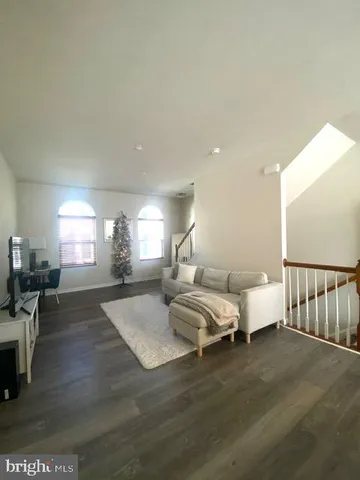 a living room with couches chairs and a dining table with wooden floor