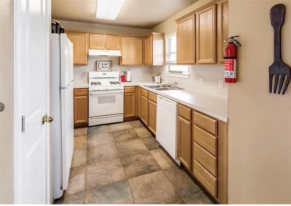 a kitchen with a sink cabinets appliances and a window