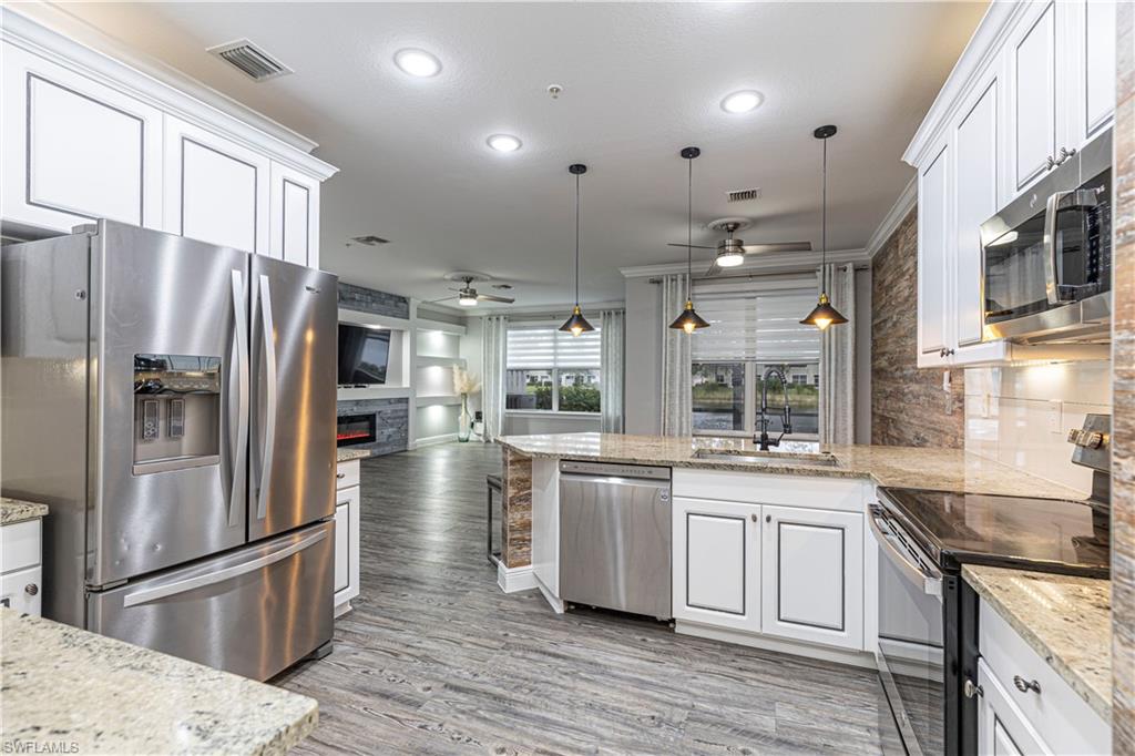 1330 Mariposa Circle, Unit 103 Naples, FL 34105 - Photo 11 of 32 a kitchen with stainless steel appliances granite countertop a refrigerator a sink a stove and oven