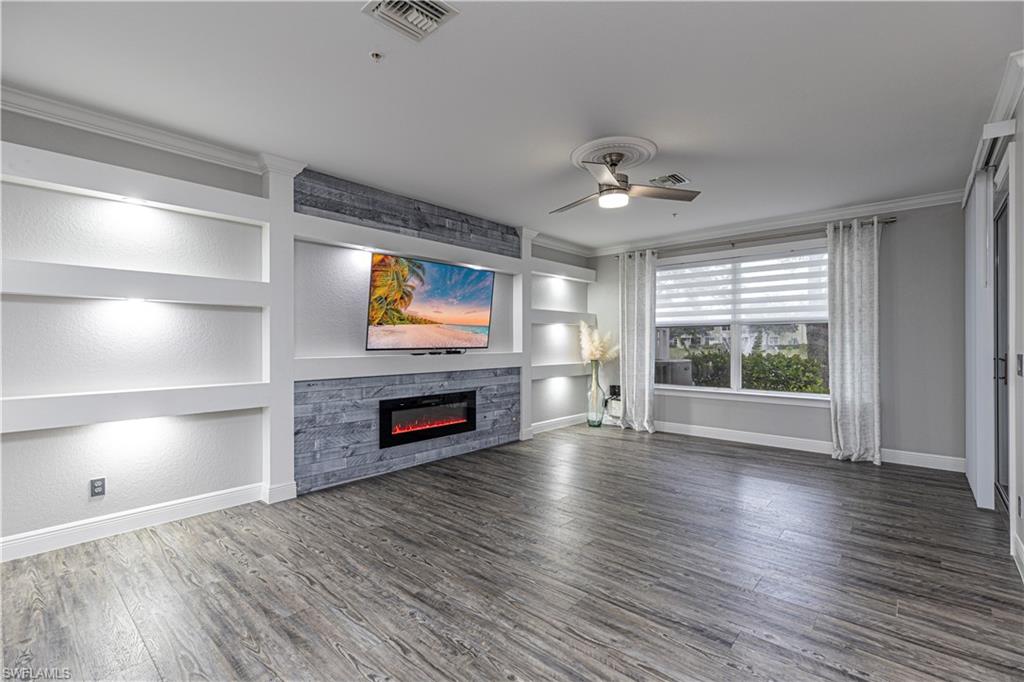 1330 Mariposa Circle, Unit 103 Naples, FL 34105 - Photo 12 of 32 a view of empty room with fireplace and wooden floor