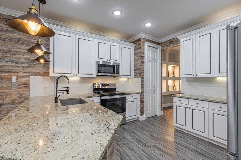 1330 Mariposa Circle, Unit 103 Naples, FL 34105 - Photo 13 of 32 a kitchen with stainless steel appliances granite countertop a stove a sink and a microwave