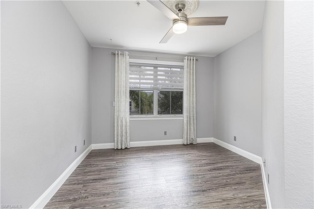 1330 Mariposa Circle, Unit 103 Naples, FL 34105 - Photo 17 of 32 an empty room with wooden floor and windows