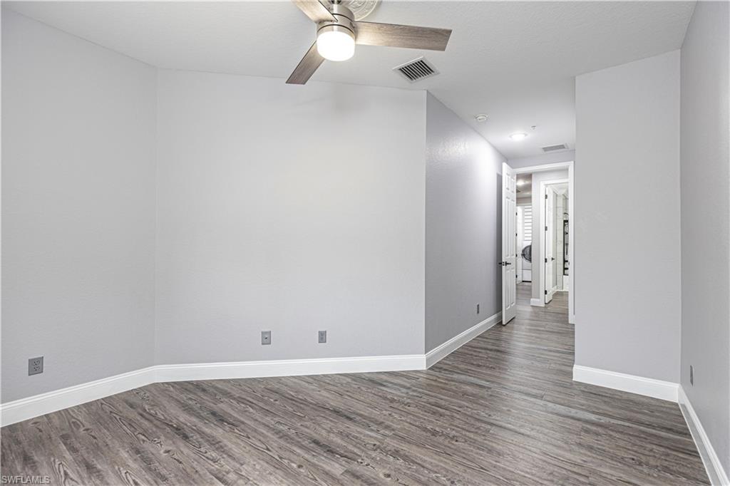 1330 Mariposa Circle, Unit 103 Naples, FL 34105 - Photo 18 of 32 an empty room with wooden floor and windows