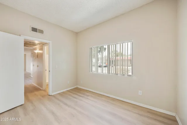 a view of an empty room with wooden floor and closet