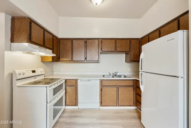 a kitchen with a refrigerator a stove top oven a sink and cabinets