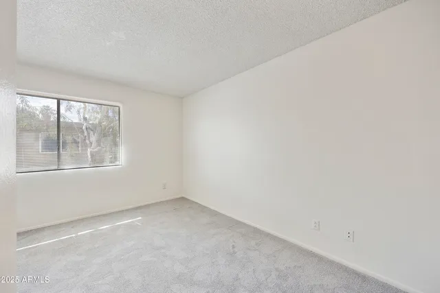 a view of an empty room with closet and a window
