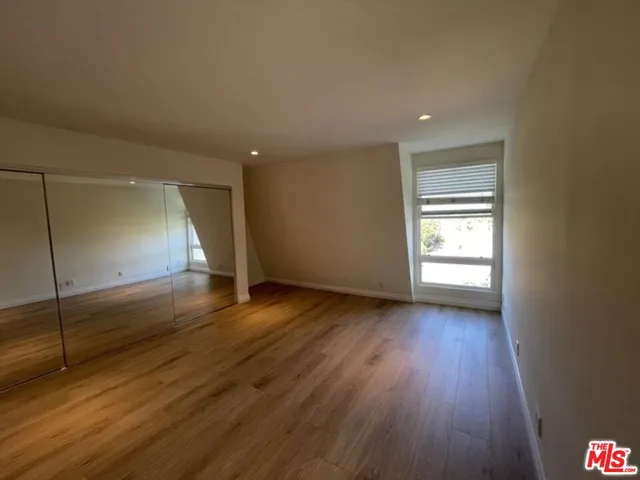 an empty room with wooden floor and window