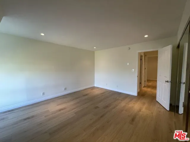 an empty room with wooden floor and entrance