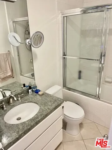 a bathroom with a granite countertop sink toilet a mirror and shower