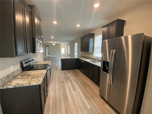 a kitchen with stainless steel appliances granite countertop a refrigerator and a sink