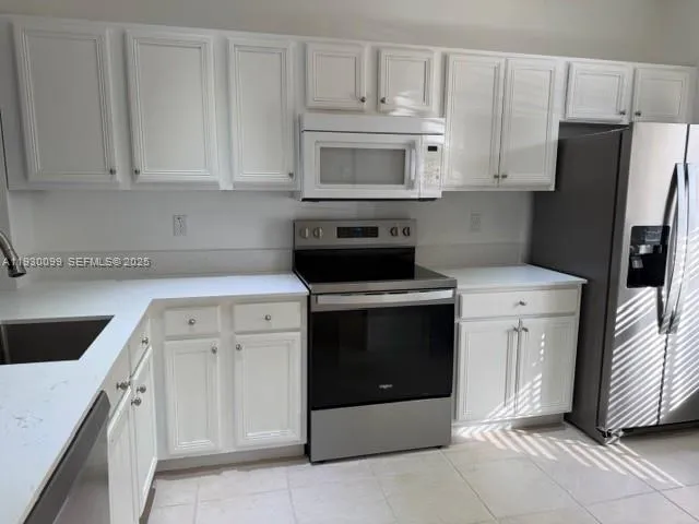 a kitchen with white cabinets and stainless steel appliances
