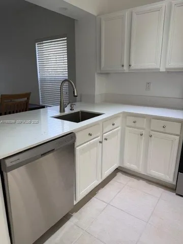 a kitchen with white cabinets and sink
