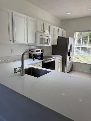 a kitchen with kitchen island granite countertop a sink stove and refrigerator
