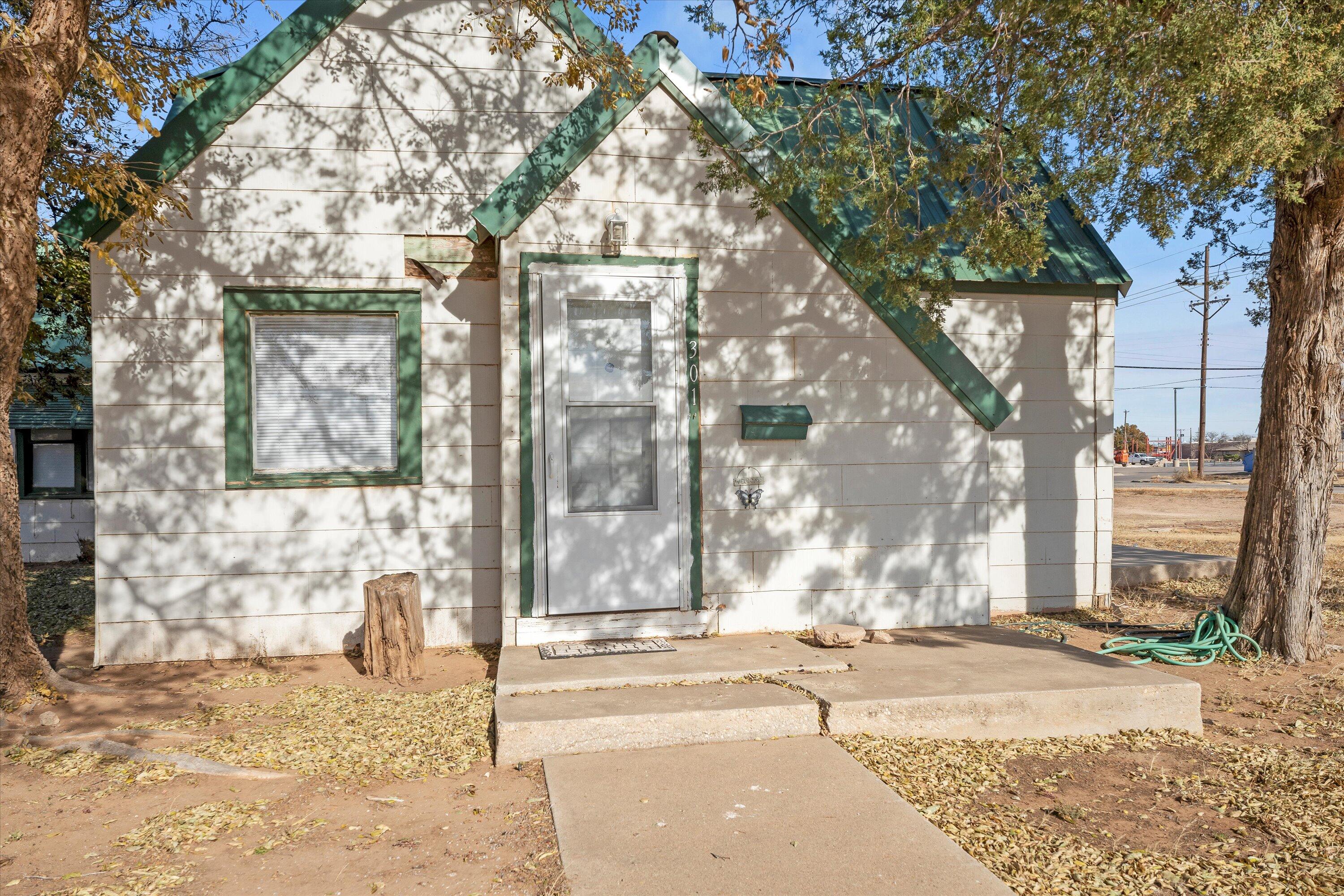 301 Austin Street Levelland, TX 79336 - Photo 2 of 18 a view of a brick house with large tree and wooden fence