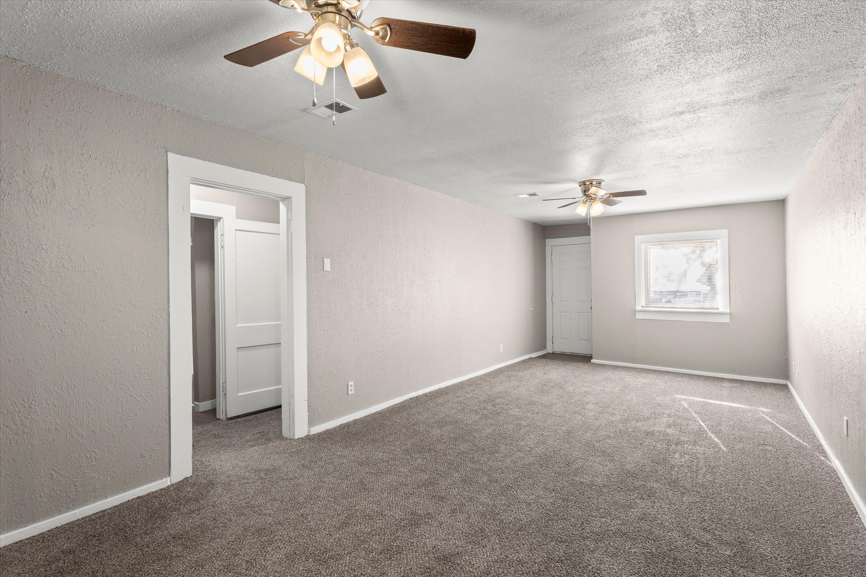 301 Austin Street Levelland, TX 79336 - Photo 4 of 18 en empty room with windows and ceiling fan