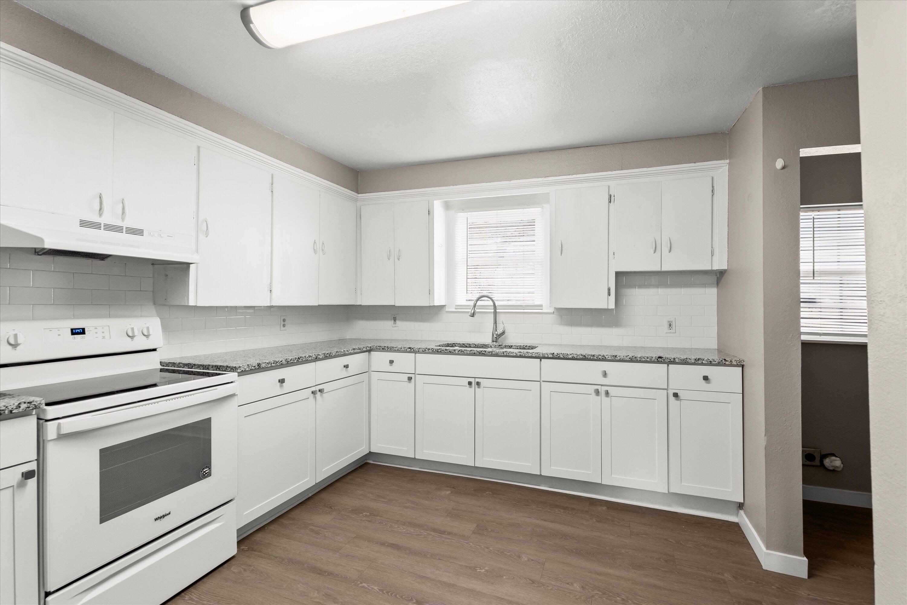 301 Austin Street Levelland, TX 79336 - Photo 6 of 18 a kitchen with granite countertop white cabinets and white appliances