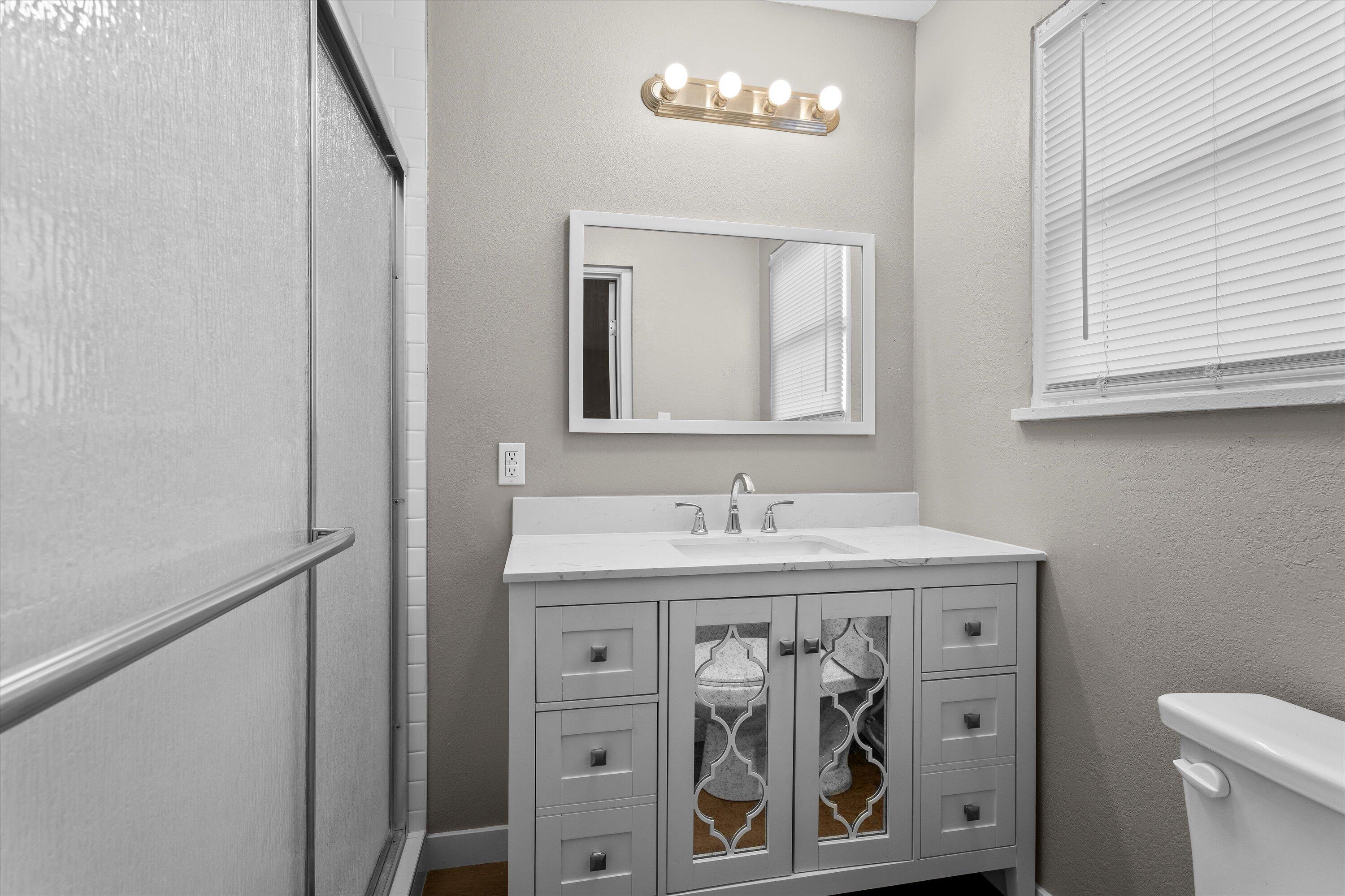 301 Austin Street Levelland, TX 79336 - Photo 10 of 18 a bathroom with a toilet a sink and a mirror