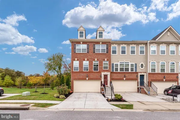 a front view of a house with a yard and trees in the background