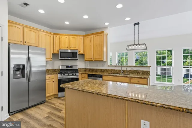 a kitchen with stainless steel appliances granite countertop a sink a stove and a refrigerator