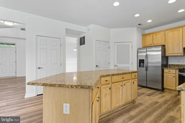 a kitchen with stainless steel appliances granite countertop a refrigerator a sink and white cabinets