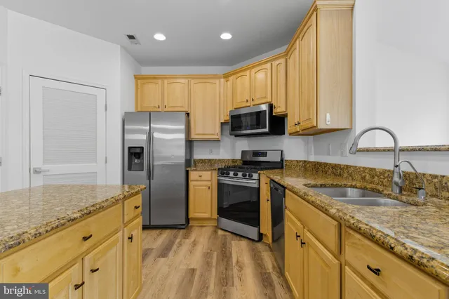 a kitchen with granite countertop a sink stainless steel appliances and counter space