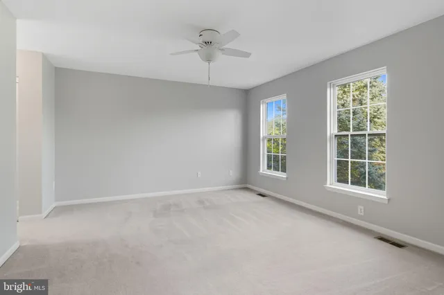 an empty room with a window and a ceiling fan