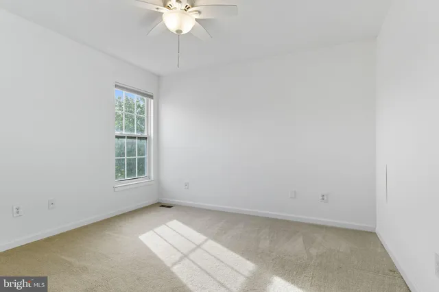 an empty room with chandelier fan and windows