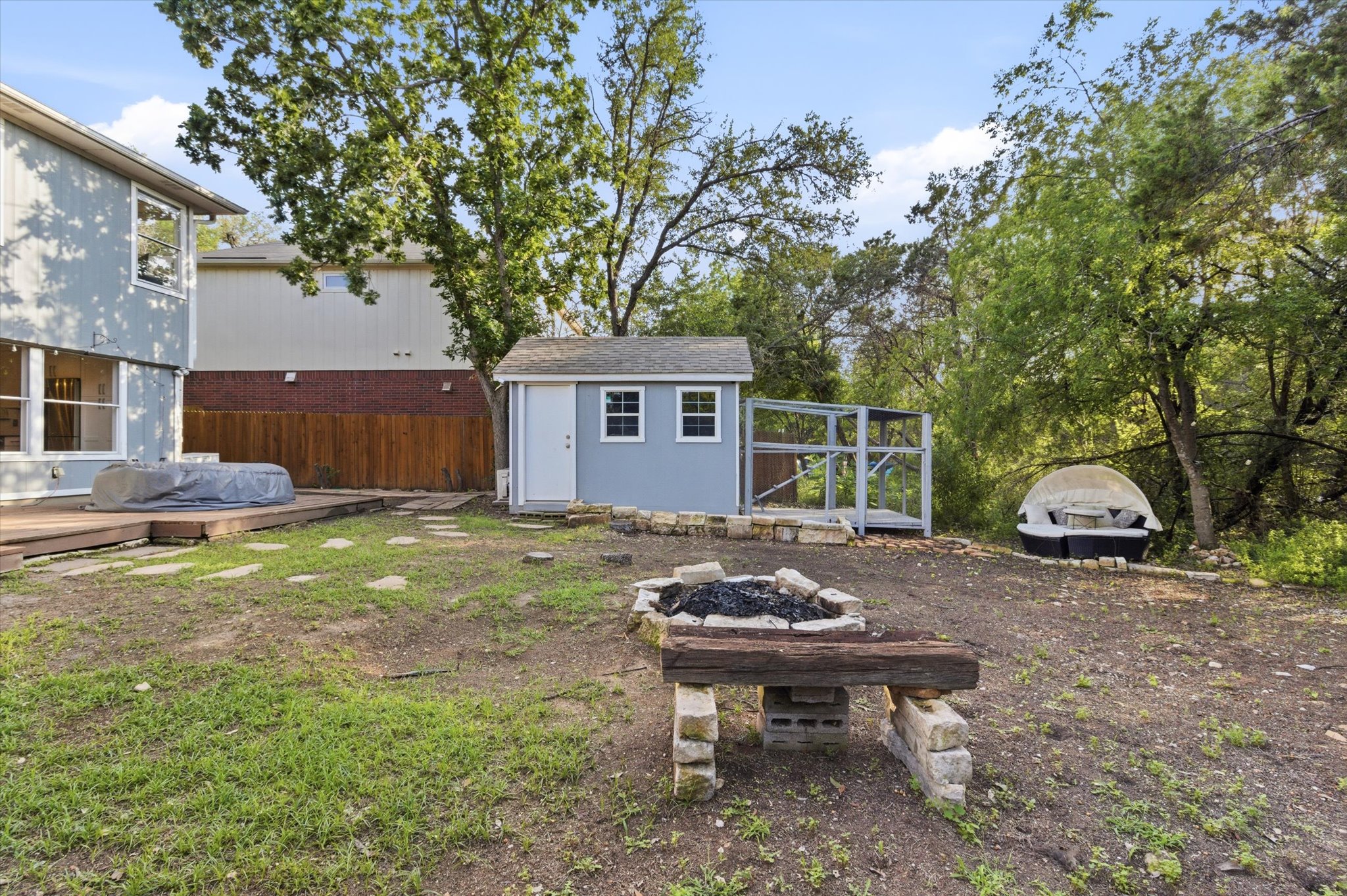 8920 West Hove Loop Austin, TX 78749 - Photo 37 of 39 Expansive backyard featuring a wood deck, stone fire pit, and a detached shed with an enclosed run