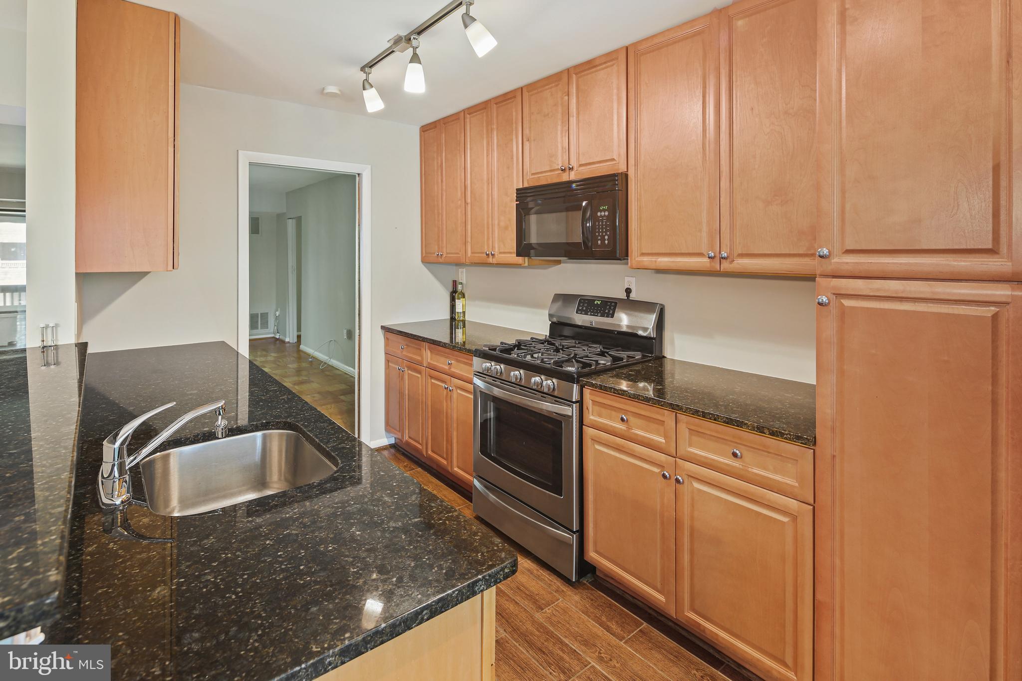 5239 West Running Brook Road, Unit 301 Columbia, MD 21044 - Photo 30 of 33 a kitchen with stainless steel appliances granite countertop a sink stove and microwave