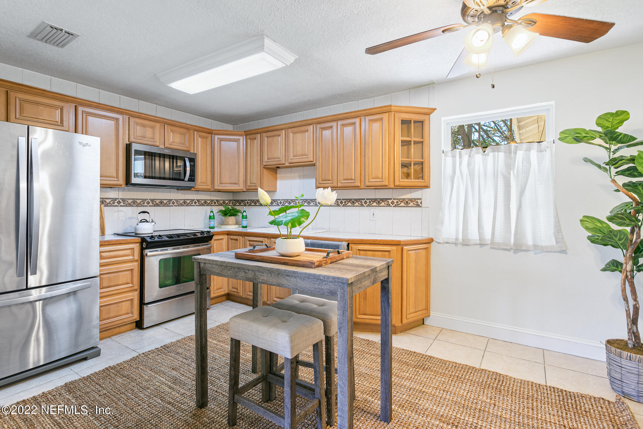 4631 Tanbark Road Jacksonville, FL 32210 - Photo 5 of 27 a kitchen with a refrigerator a stove a sink a dining table and chairs with wooden floor
